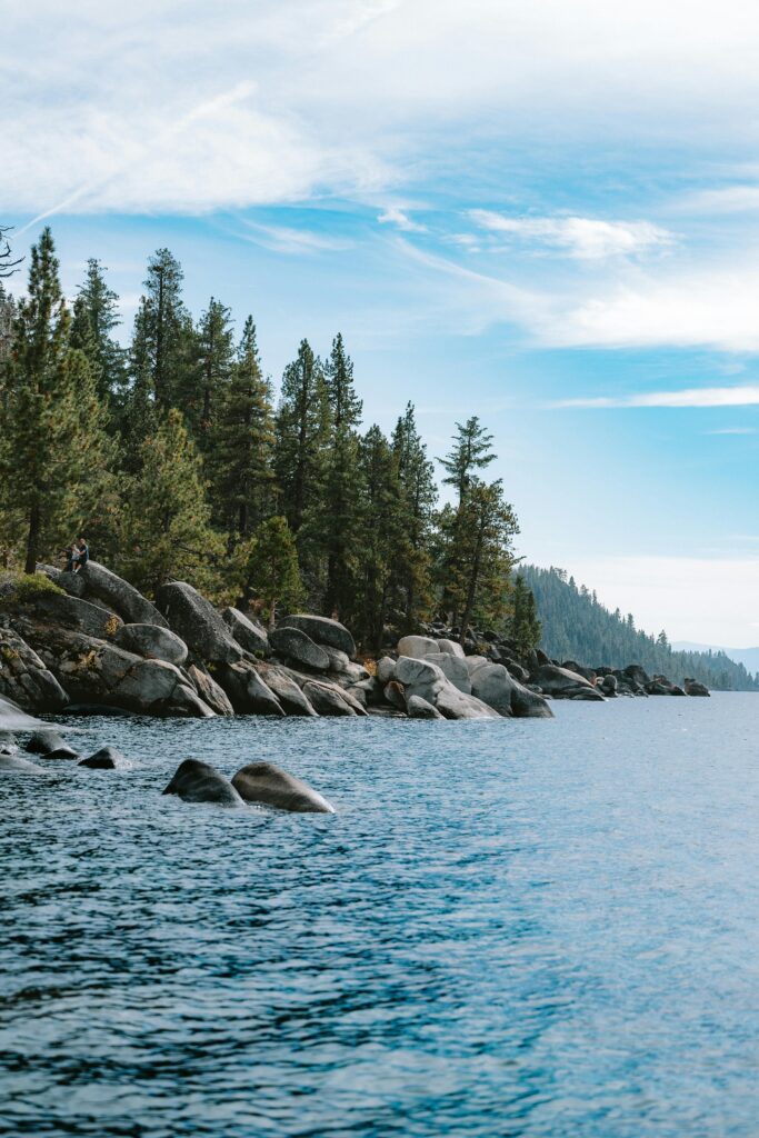 Serene view of South Lake Tahoe's rocky shoreline with coniferous forest background.